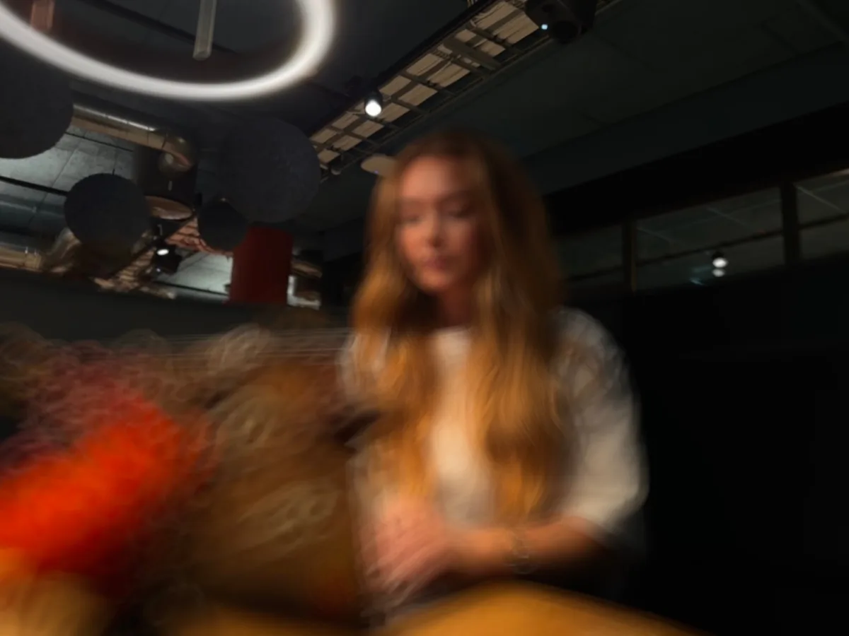 Blurred photo from Moodlabbet: a person at a table under a ring-shaped ceiling light.