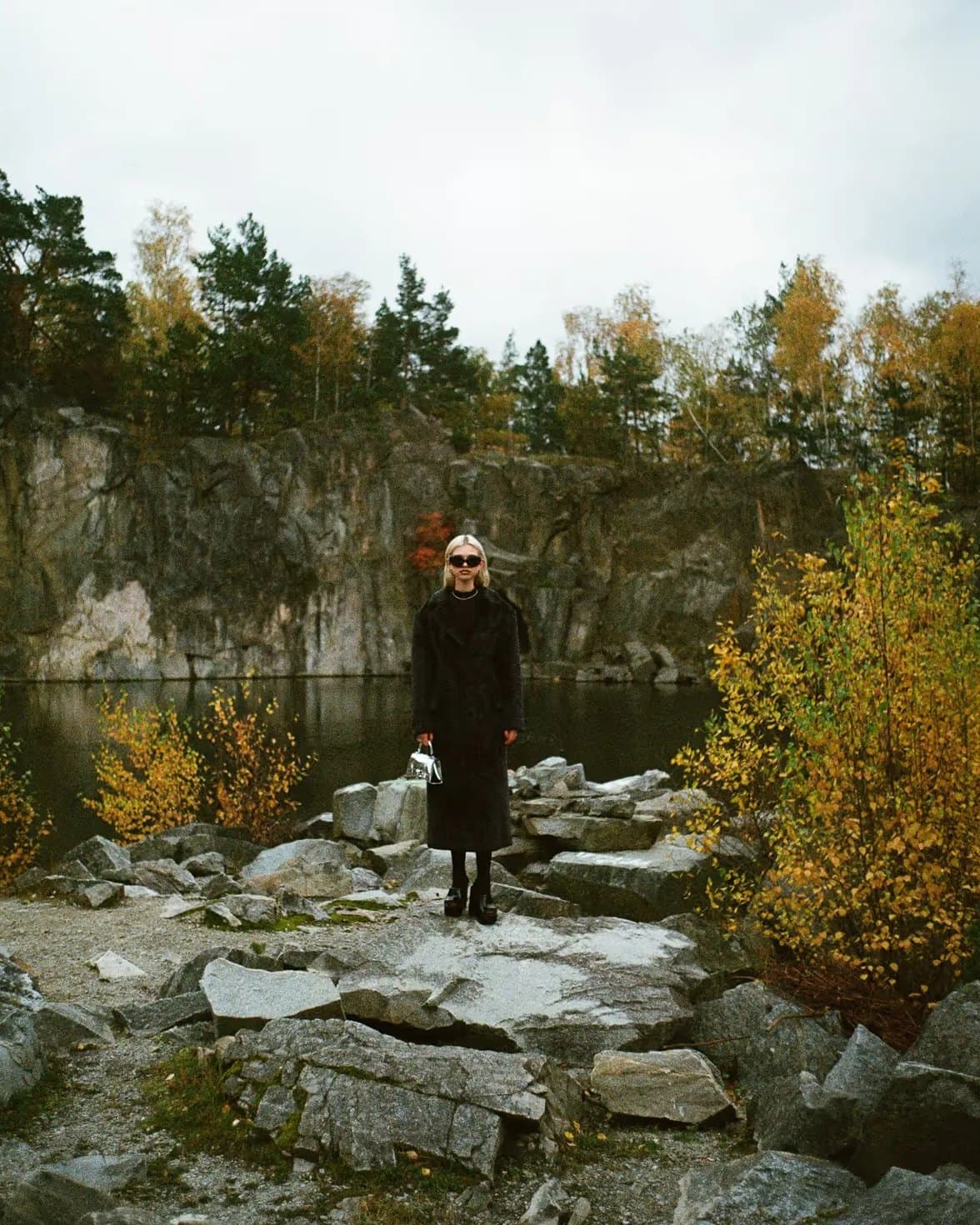 A person in a dark coat standing among the rocks of a quarry in autumn. Photo: Petter Bülling.